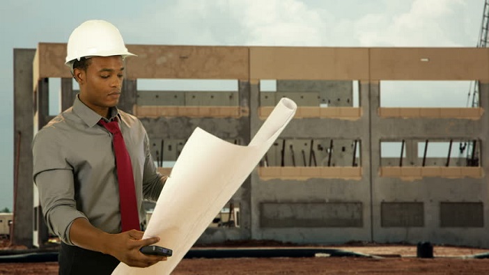 Architect reviewing building design plans and 3D models in a construction project office