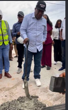 Dave Umahi shovels concrete at a road construction site.