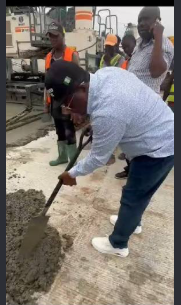Dave Umahi shovels concrete at a road construction site.